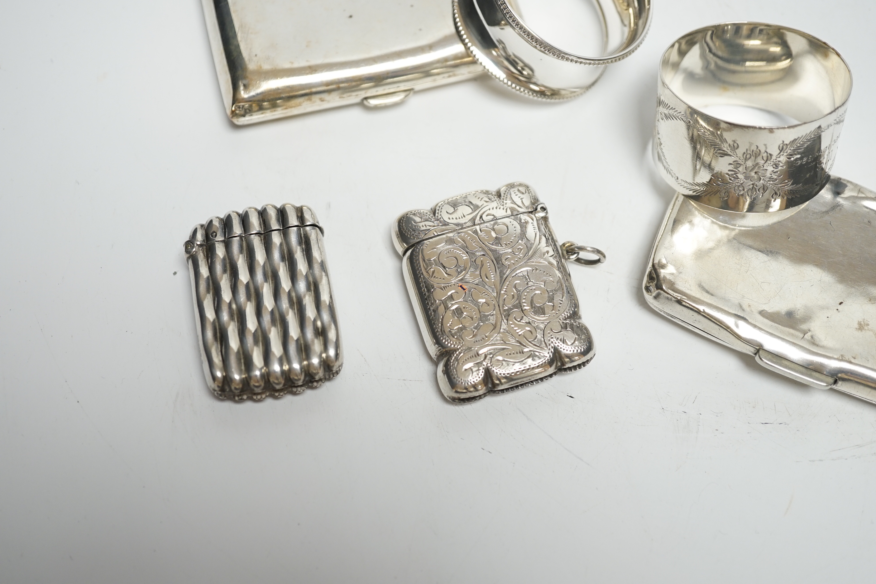 Two silver napkin rings, two silver cigarette cases and two silver vesta cases.